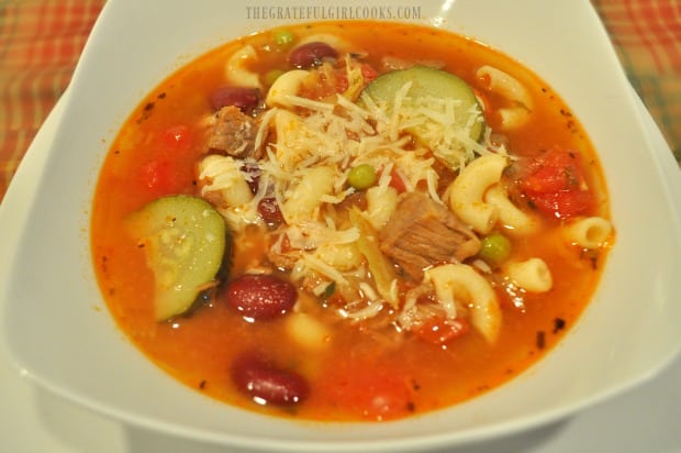 A bowl of hearty minestrone soup, topped with grated Parmesan cheese.