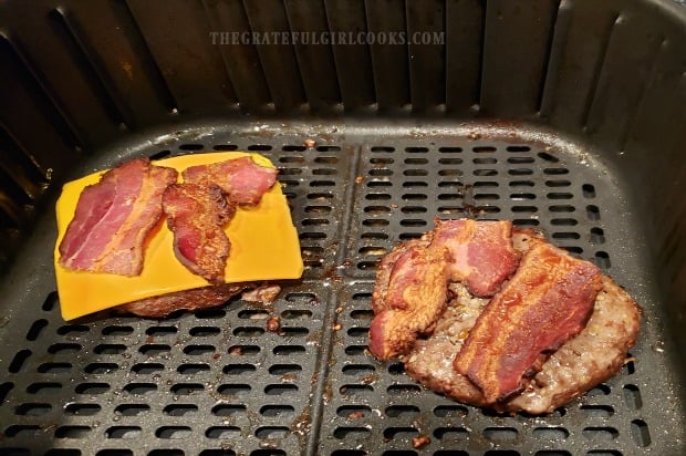 Bacon slices, cheddar cheese added to air fryer bacon cheeseburger.