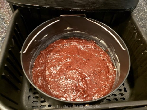 The pan full of brownie batter is placed into an air fryer to cook.