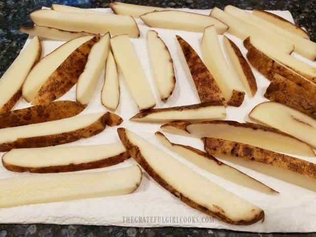 The fries are patted dry before oil and seasoning are added.