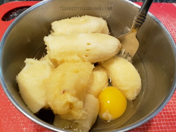 Ripe bananas, an egg, and vegetable oil are mixed together in medium bowl.