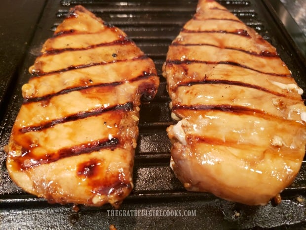 Chicken breasts with homemade teriyaki marinade cooking on cast iron grill.