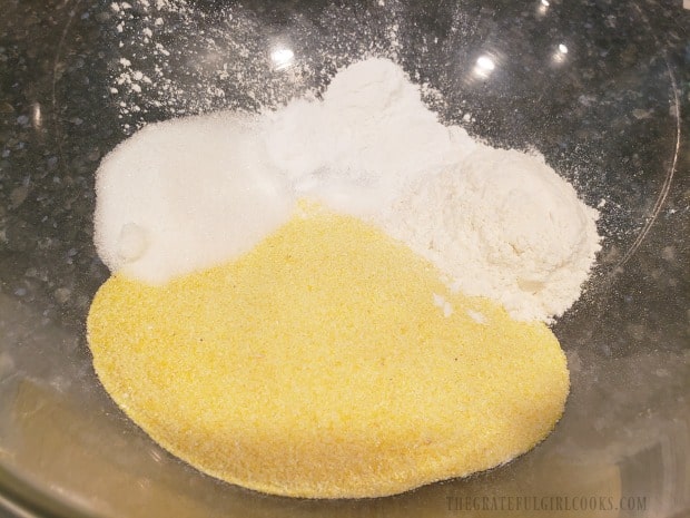 The dry ingredients for cornbread batter are added to a large mixing bowl.