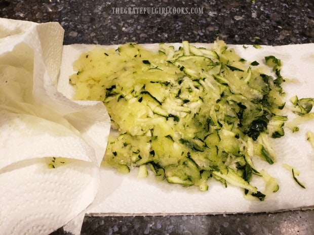 Unpeeled zucchini is grated, then dabbed with paper towels to absorb moisture.