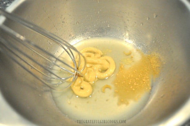 Lemon juice, ground ginger, and Dijon mustard are whisked together in bowl.
