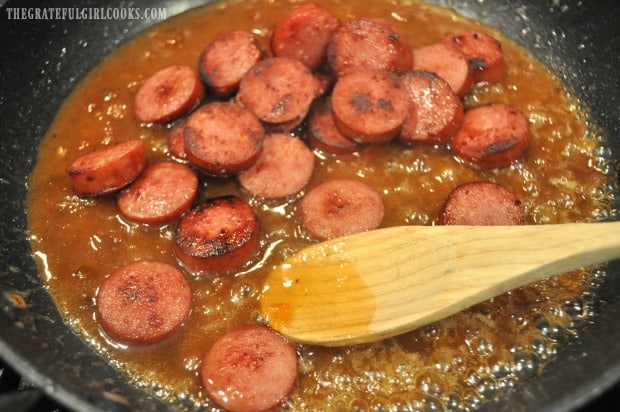 The cooked kielbasa slices are added back into the skillet with apricot pineapple glaze.