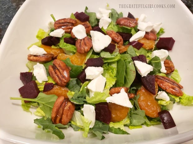 Candied pecans and crumbled goat cheese are added to the salad.