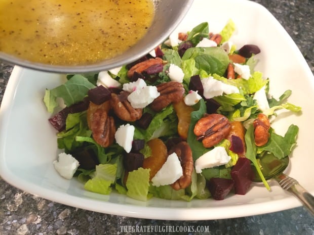 A citrus dressing is poured over the beet and goat cheese salad before serving.