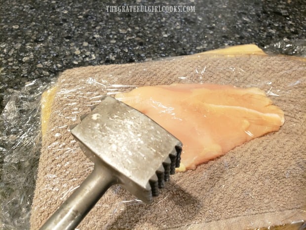 Chicken breasts are pounded until 1/4" thick between pieces of plastic wrap.