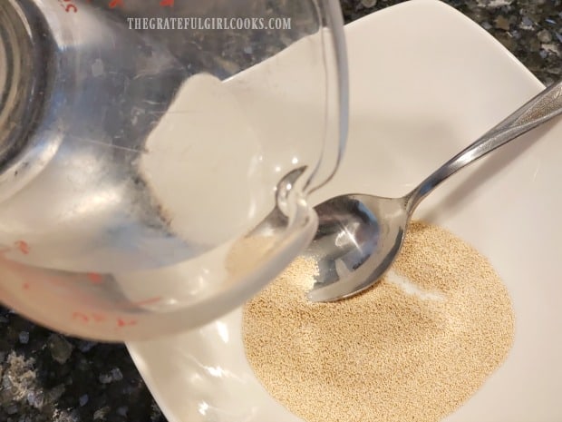 the heated water is added to the bowl of yeast and granulated sugar.