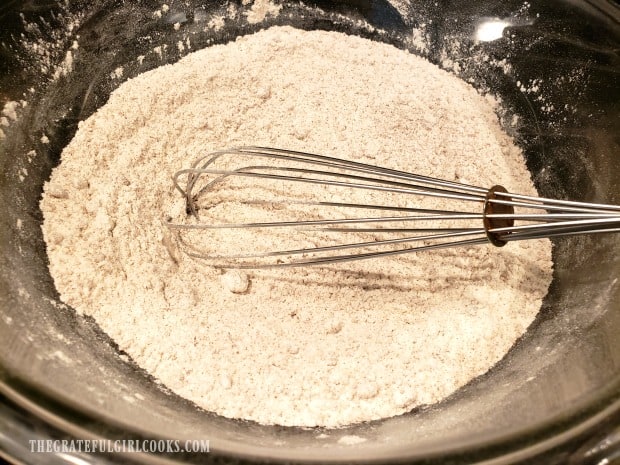 Dry ingredients for doughnuts are whisked together in bowl.
