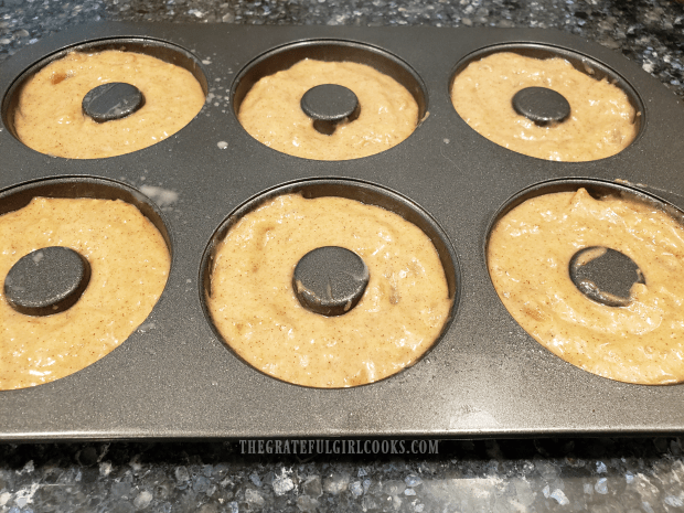 The doughnut batter is placed into a doughnut baking pan to cook.