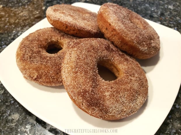 A plate with four of the apple cinnamon baked doughnuts, ready to eat.
