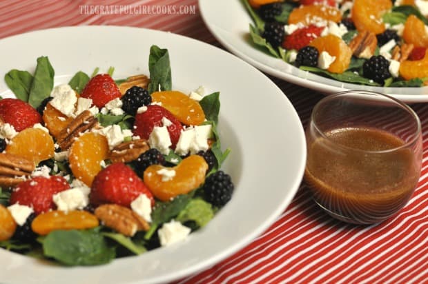 Two salads, with a small container of citrus balsamic vinaigrette on the side.