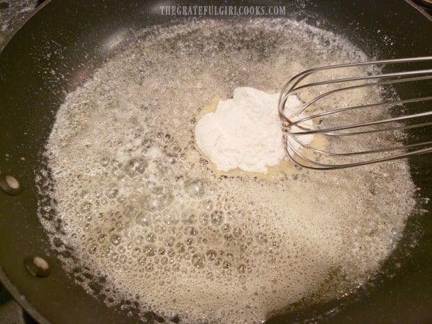 Flour, and then whipping cream is whisked into melted butter in skillet.