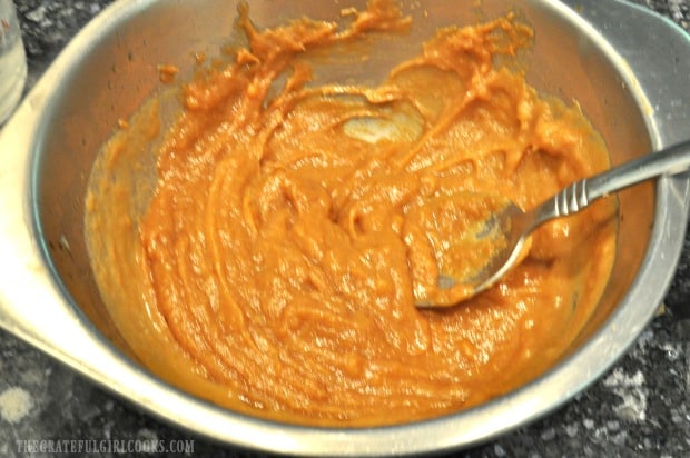 Peanut sauce in grey bowl is beginning to become creamy by stirring ingredients.