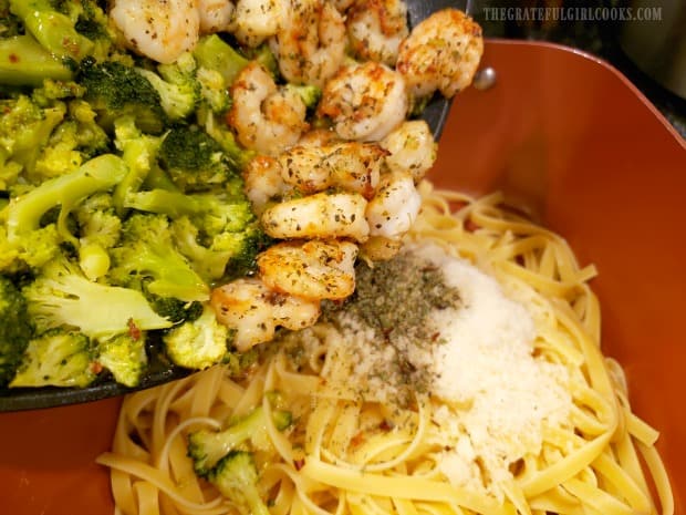 Cooked shrimp and broccoli are added to the pasta, then gently mixed together.