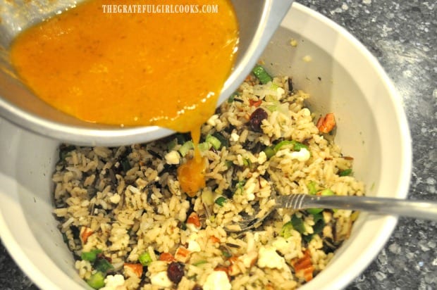 The finished pumpkin vinaigrette is poured over wild rice salad and then served.