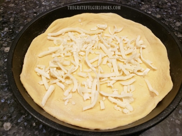 Sprinkle the bottom of the crust with some of the grated mozzarella cheese.