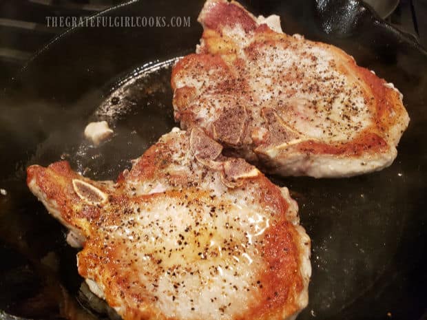The pork chops are seared until browned, and then flipped to cook the other side.