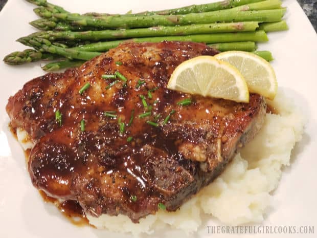 The brown sugar pork chops are served on mashed potatoes, with asparagus on the side.