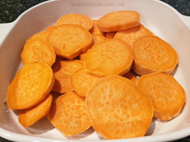 Peeled, fresh sweet potato rounds are placed into a greased baking dish.