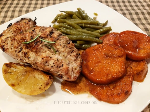 Candied sweet potatoes on plate with grilled lemon chicken and green beans.