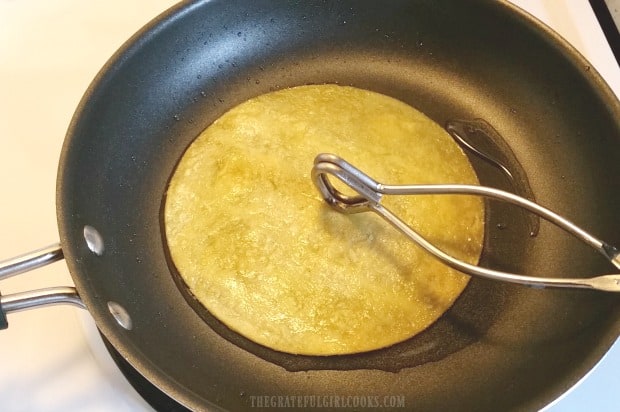 Corn tortillas are quickly fried in hot oil to soften before adding enchilada filling.