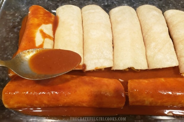 Additional enchilada sauce is put on top of the enchiladas in the baking pan.