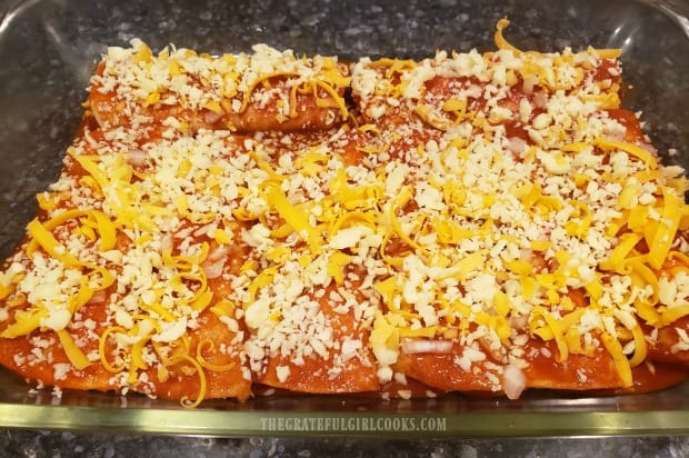 Grated cheeses are sprinkled on top of the easy cheesy enchiladas before baking.