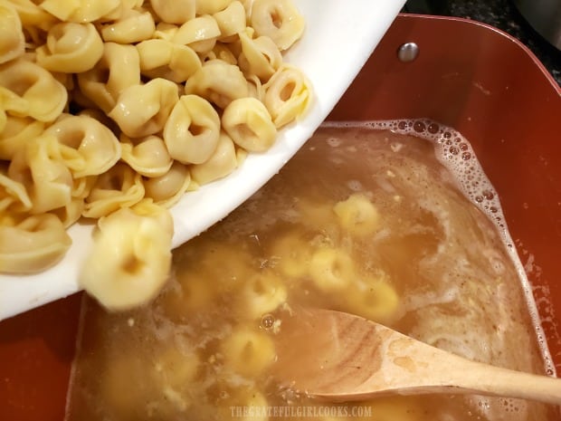 Cooked and drained tortellini is added to the broth in the soup pan.