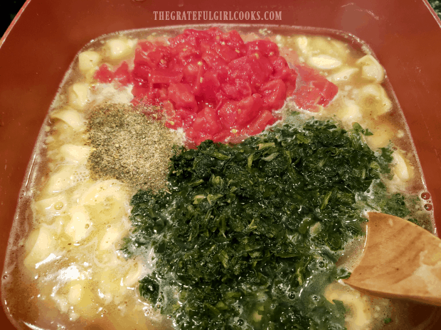 Drained spinach, tomatoes, and spices are added to the tortellini soup.