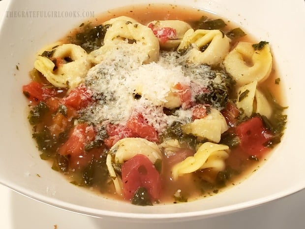 The finished tortellini soup is topped with finely grated Parmesan cheese.