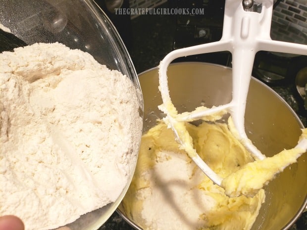 Dry ingredients (flour, baking powder, salt) are slowly added to muffin batter in batches..