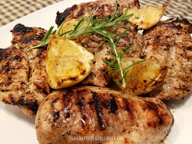 Grilled Lemon Chicken Breasts are served, garnished with charred lemon wedges and rosemary sprigs.