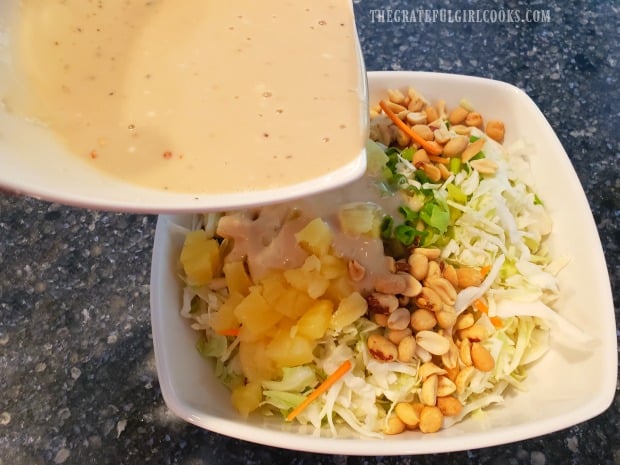 The salad dressing is added to the bowl of pineapple peanut coleslaw.