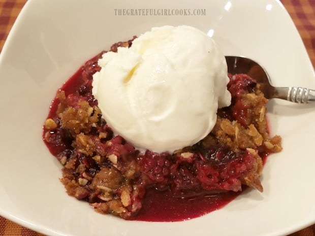 A la mode blackberry crisp, served in white bowl.