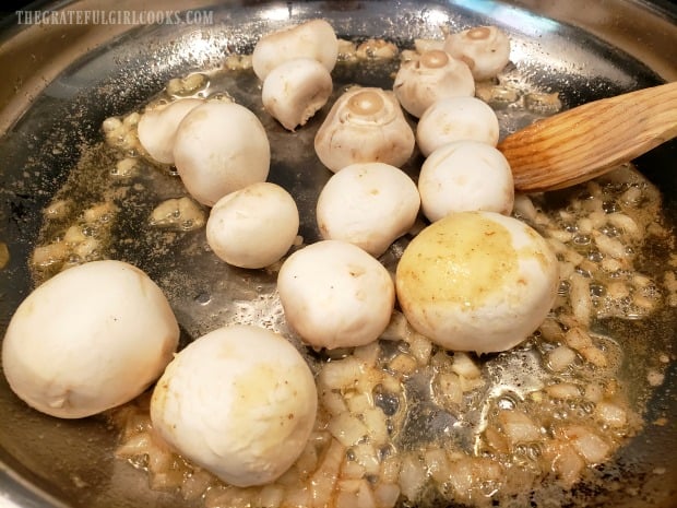 Whole, cleaned mushrooms are added to the skillet.