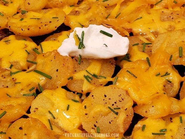 The final garnish for the cheesy skillet potatoes is a dollop of sour cream.