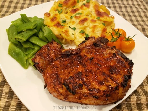 Awesome Grilled Pork Chops, served with scalloped potatoes, green beans, and tomatoes.
