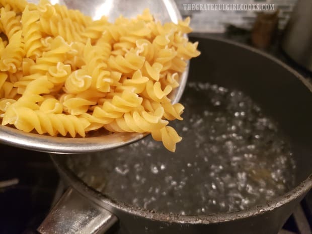 Adding pasta to boiling water to cook.