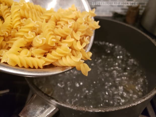 Adding pasta to boiling water to cook.