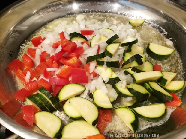 Bell peppers, zucchini, and onion are cooked in butter.