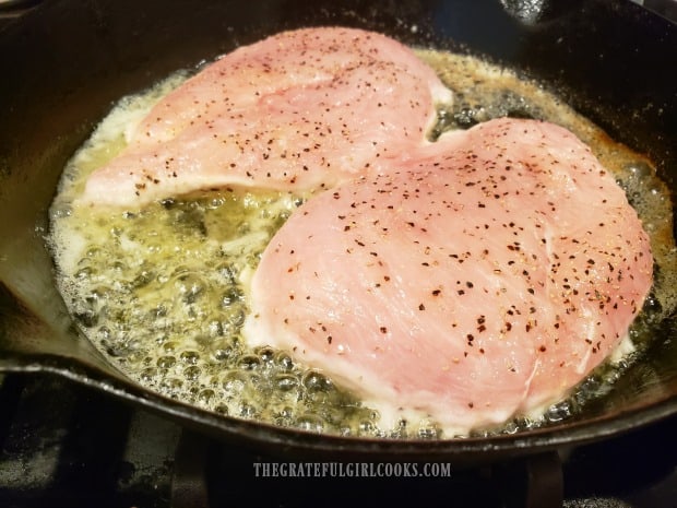 Pan-searing the chicken breasts in melted butter in a black cast iron skillet.