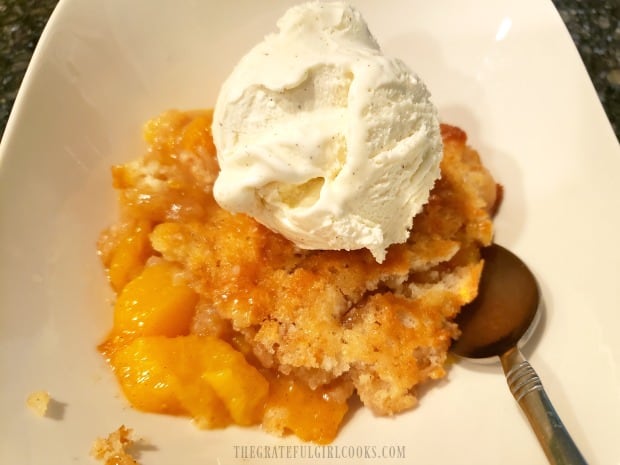 Fresh peach cobbler is served a la mode with vanilla bean ice cream.