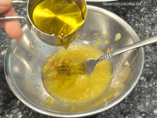 Olive oil is slowly drizzled into salad dressing while whisking.
