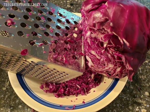 Purple cabbage for the coleslaw is grated into a large bowl.