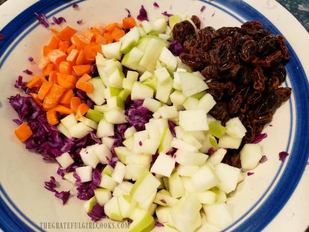 Chopped carrots, apples, and raisins are added to the grated purple cabbage.