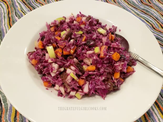 The colorful poppyseed apple raisin coleslaw is served in a large white bowl.