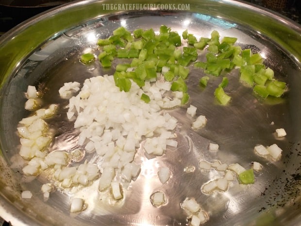 Chopped green pepper and onions are cooked in olive oil in skillet.